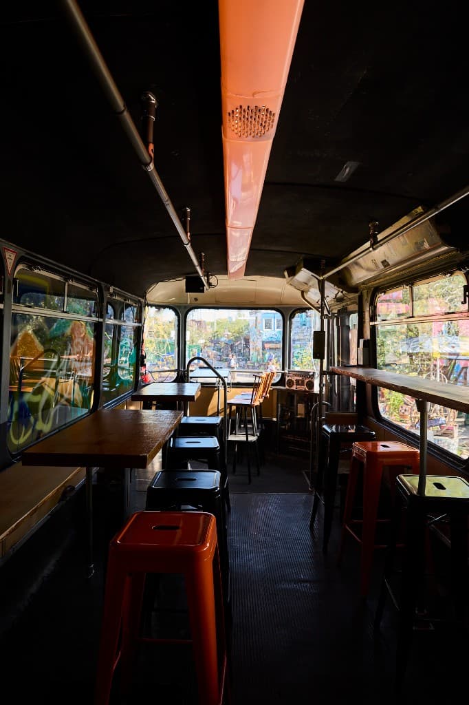 Innenraum des Waggons mit orangefarbenen Hockern und Fenstern